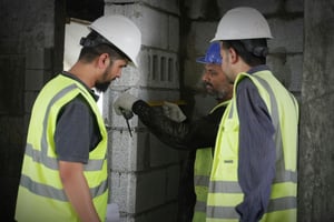 Three construction workers inspecting a wall
