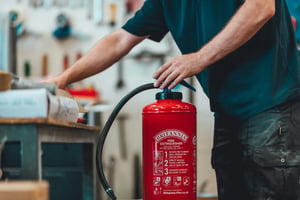 Man works beside work bench with Britannia Fire fire extinguisher